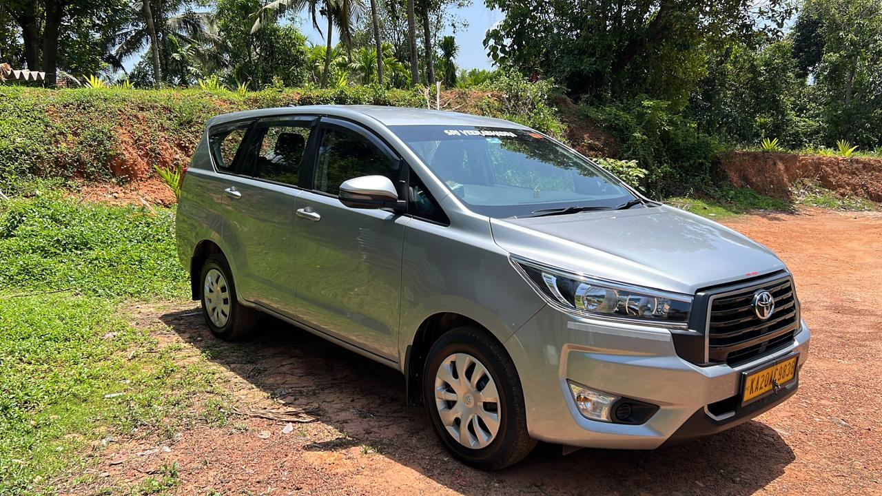 Silver Toyota Innova Crysta parked in a green area